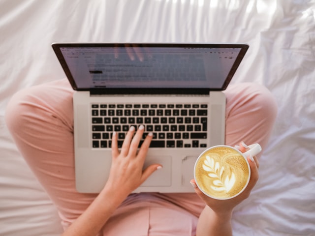 woman volunteering from home on her laptop drinking a latte